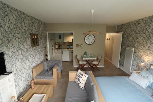 un salon avec un canapé et une horloge au mur dans l'établissement Les Platanes, à Saint Lo