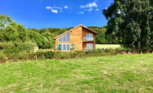 a log cabin in a field next to a yard at Blackdown Views - New 6 Bedroom Eco House in Dunkeswell