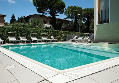 una piscina con tumbonas y sillas en Sirmione Rosselli Apartments en Sirmione