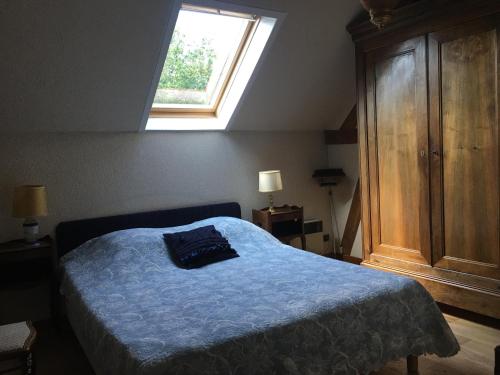 een slaapkamer met een bed met een blauwe deken en een raam bij LA MAISON DE LUCIE in Veuil