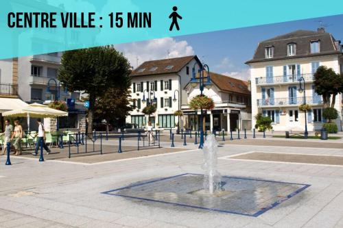 a fountain in a square in a city with buildings at La Source d'Arbère in Divonne-les-Bains
