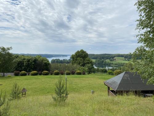 a barn in a field with a view of a lake at Leśny domek in Chmielno