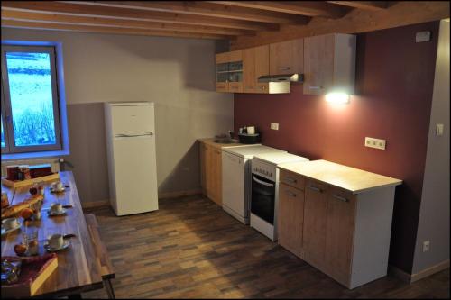 a kitchen with a white refrigerator and a table at Gîte des Deux Rieu in Grandrieu