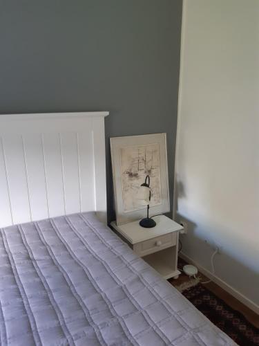 a bedroom with a bed and a lamp on a nightstand at The Cottage Badelunda in Västerås