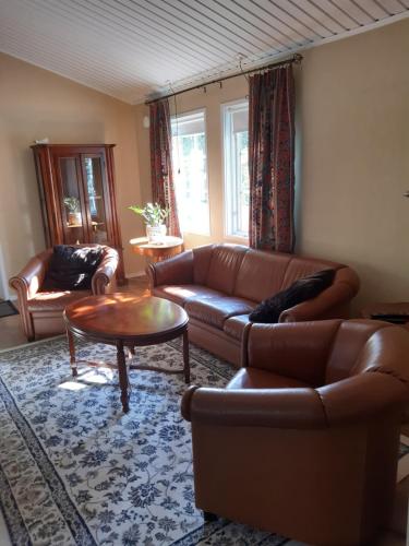 a living room with a leather couch and a table at The Cottage Badelunda in Västerås