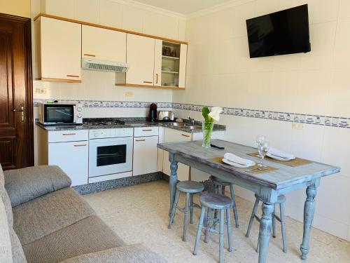 a kitchen with a table with chairs and a tv at Pensión San Antón in Sanxenxo