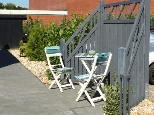 ビューズムにあるHaus-Norderpiepの柵の横の椅子2脚とテーブル