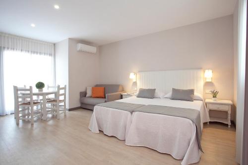 Apartamentos Ribera في بنيدورم: غرفة نوم بيضاء مع سرير كبير وأريكة