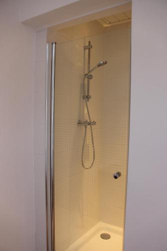 La salle de bains est pourvue d'une douche avec une porte en verre. dans l'établissement B&B de Dorpsdokter, à Udenhout