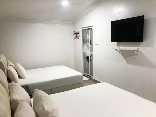 a room with two beds and a flat screen tv at HOTEL SHAFURA 2 in Cukai