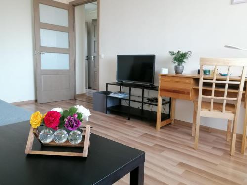 uma sala de estar com uma mesa com flores e uma televisão em Apartment Anna em Saldus