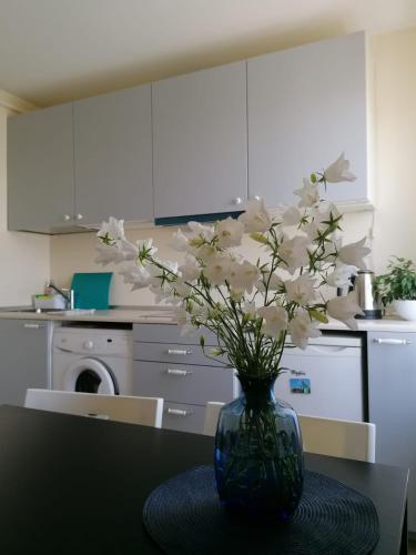 a vase with white flowers on a table in a kitchen at Apartment Anna in Saldus