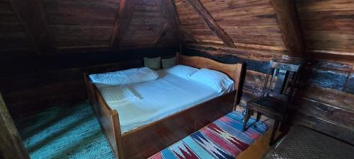 1 dormitorio con 1 cama en una cabaña de madera en Satul Traditional, en Runcu