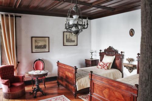 a bedroom with a bed and a chair and a chandelier at Quinta do Regalo in Coimbra