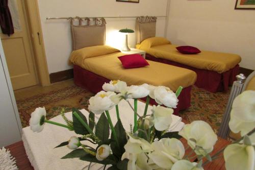 um quarto de hotel com duas camas e um vaso de flores em Guesthouse City Center em Bari