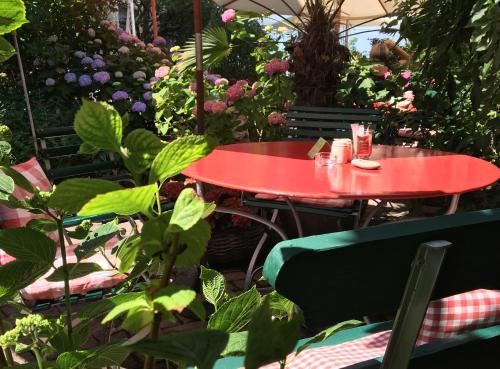 a red table in a garden with plants and flowers at Hotel Mozart in Rorschach