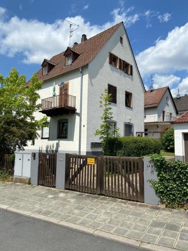 a white house with a wooden gate and a fence at Zirndorf Ferienhaus in Zirndorf