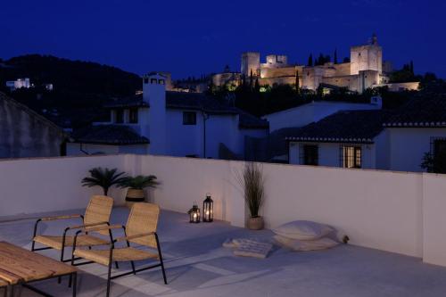 een patio met 2 stoelen en 's avonds een tafel bij FERALA SUITES ALBAYZíN in Granada