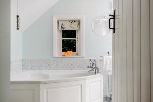 baño con lavabo blanco y ventana en Beck Cottage, Wood Green, New Forest UK en Breamore