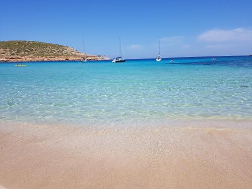 a beach with blue water and boats in the ocean at Fiframar in Sant Josep de Sa Talaia
