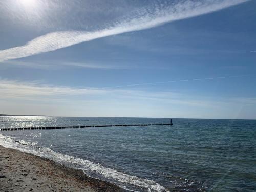 a beach with a pier in the ocean at Fewo Strandleben Haus Strandperle in Börgerende-Rethwisch