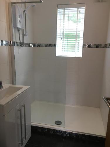 baño blanco con ducha y lavamanos en Ground floor 2 bed apartment in central location with private access to 7 miles of sandy beach (sleeps 4), en Brean