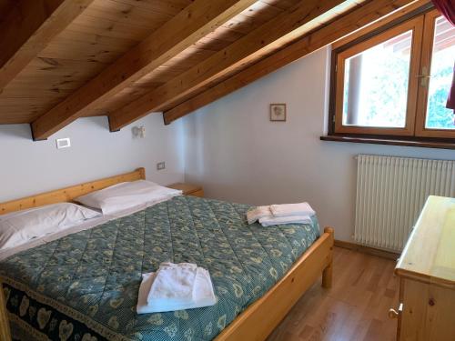 a bedroom with a bed with a green comforter and a window at Residence Trunka Lunka in Cavalese