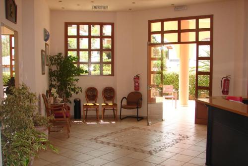 a living room with chairs and tables and windows at Georges Estates Hotel in Stoupa