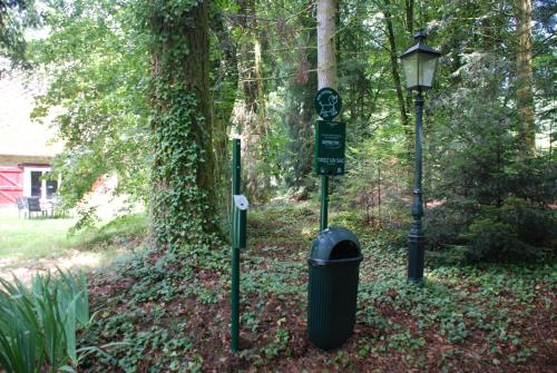 a street signs and a trash can next to a tree at B&B Chateau le Bois in Saint-Julien-aux-Bois