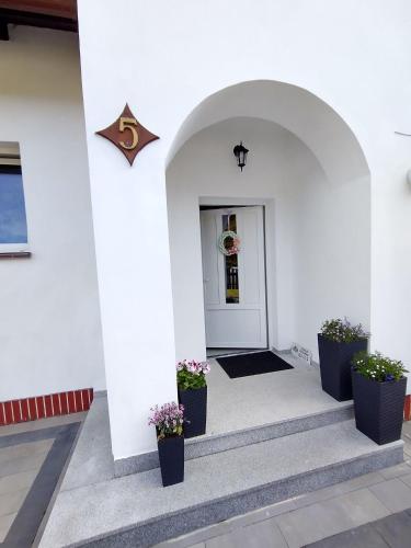 a white building with potted plants in front of a door at Willa Karwia in Karwia