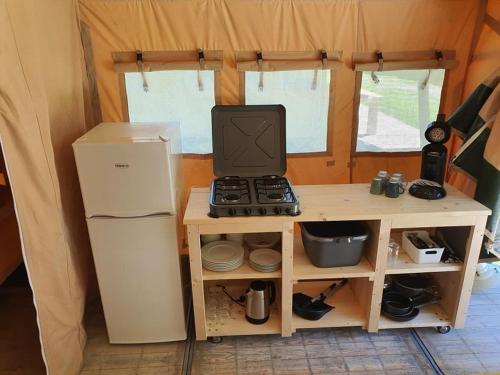 a small kitchen with a stove and a refrigerator at Safaritent op Camping la Douane in Vresse-sur-Semois