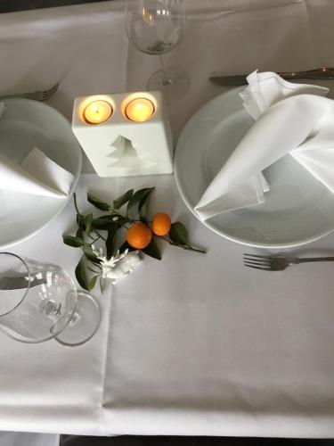 a table with two plates and candles and oranges on it at Hotel Zum Berggarten in Kassel