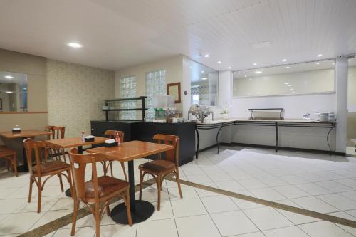 a restaurant with a table and chairs and a kitchen at Hotel Veneza in Brusque