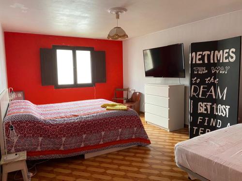 Schlafzimmer mit roten Wänden, einem Bett und einem Flachbild-TV in der Unterkunft Encantadora Boutique Home Villa Juan in Corme-Puerto