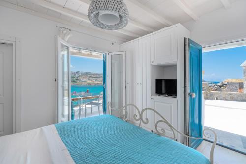 a bedroom with a bed with a view of the ocean at CORFOS BLUE MYKONOS in Ornos