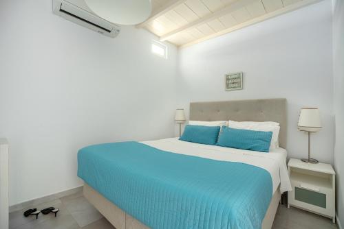 a bed in a white room with a blue bed at CORFOS BLUE MYKONOS in Ornos