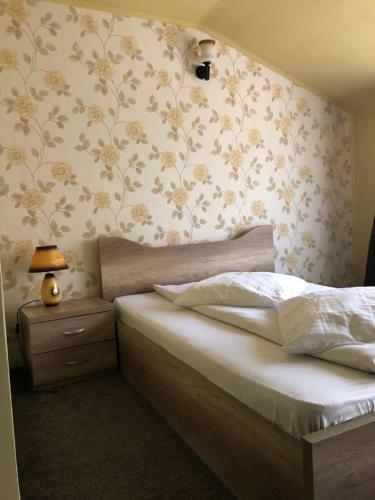 a bedroom with a bed with flowers on the wall at Pensiunea Mirela Peștera Urșilor in Chişcău