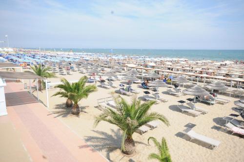 a beach with chairs and umbrellas and the ocean at Hotel Fiammetta in Rimini