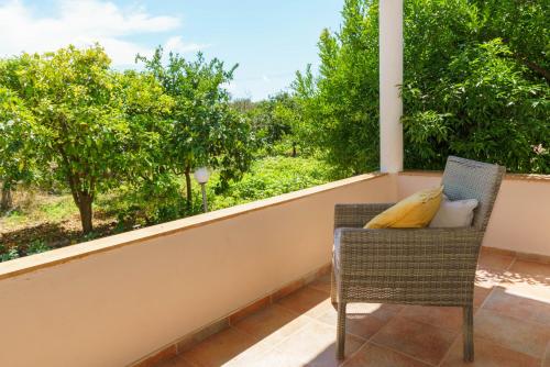 a chair with pillows on a balcony with trees at Voulamandis House in Kambos