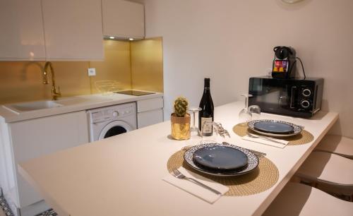 eine Küche mit einem Tisch mit Tellern und einem Waschbecken in der Unterkunft THEATRE 9 in Dijon
