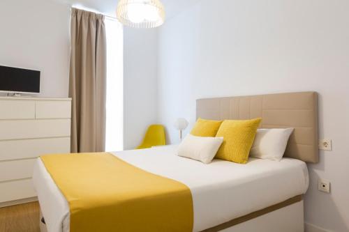 sypialnia z łóżkiem z żółtymi i białymi poduszkami w obiekcie LUMINOSO APARTAMENTO en el centro de Cádiz w Kadyksie