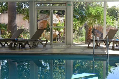 a pool with two chairs and a table next to a house at Ostella Spa & Resort in Bastia