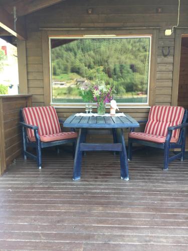 una mesa de picnic y 2 sillas en un porche en Nesheim Hytter & Camping en Bjordal