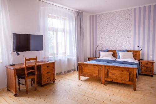 a bedroom with a bed and a desk and a television at Penzion U Madony in Česká Lípa