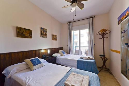 a bedroom with two beds and a ceiling fan at Apartamento Yaiza in Nerja