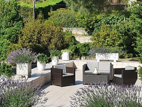 a patio with chairs and tables in a garden at Haus mit Garten über der Bucht von Cannes in Vallauris