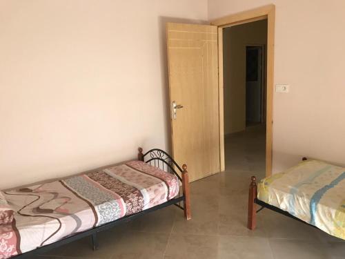 een slaapkamer met 2 bedden en een deur naar een gang bij VILLA RYAD SAIDIA in Saidia 