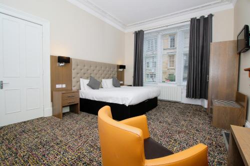 Habitación de hotel con cama y silla en City Apartments, en Glasgow