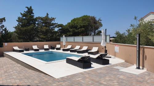 a swimming pool with lounge chairs at Poolside Hideout Apartments in Novalja