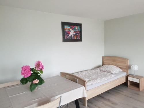 een slaapkamer met een bed en een tafel met bloemen erop bij Mainzimmer Business Appartment - Monteurwohnung mit Burgblick in Wertheim